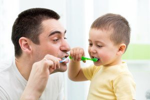 child boy and his dad brushing teeth in bathroom