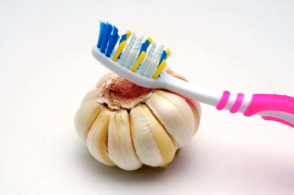 Toothbrush and garlic on white background
