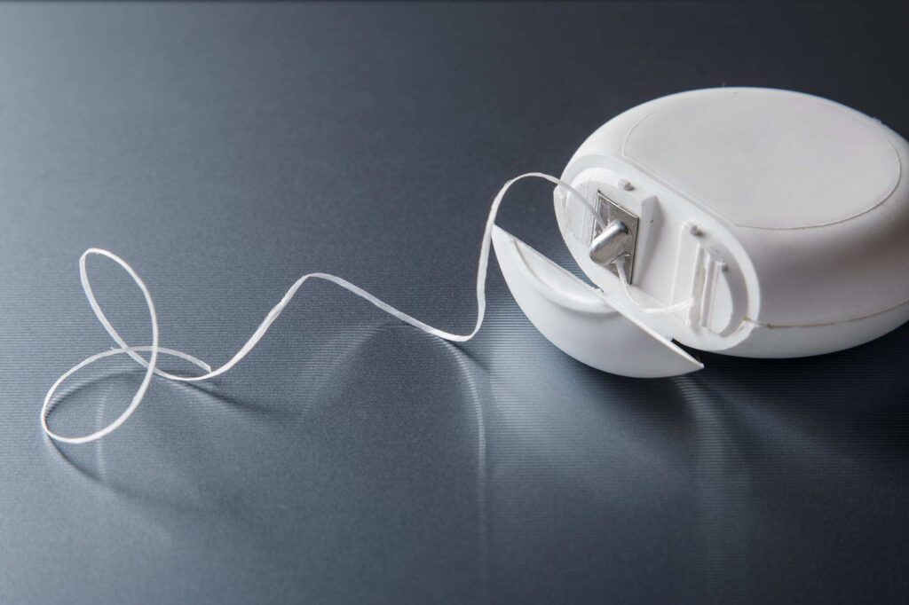 Dental floss in container on an gray background