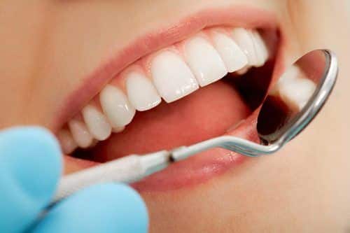 Close-up of patients open mouth during oral checkup with mirror near by