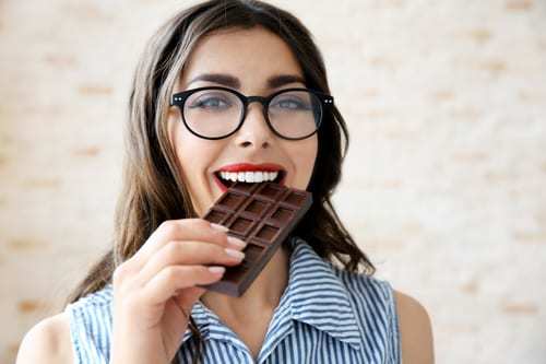 Girl eating chocolate, wearing glasses with red lipstick