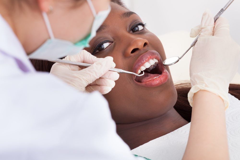 female patient whose mouth is being examined by dentist