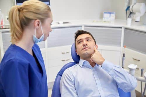male patient talking to female dentist about tooth pain