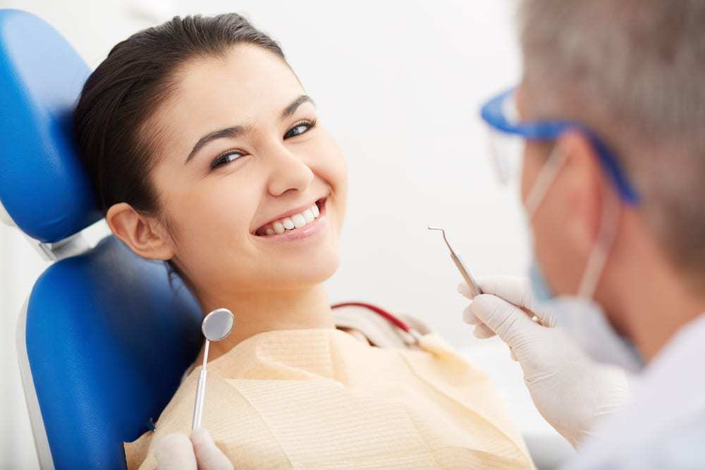 Young woman smiling at camera while sitting in dentist's chair