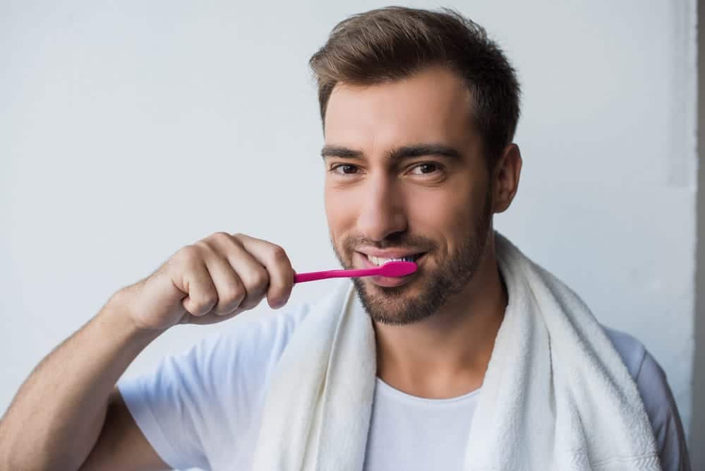 Attractive young man brushing his teeth