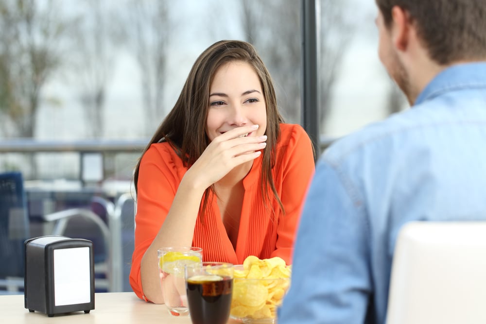 Women on date, smiling with hand over her mouth